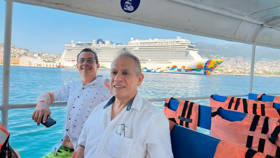 Pasajeros a bordo de Yates Dinka con un crucero atracado al fondo en Acapulco